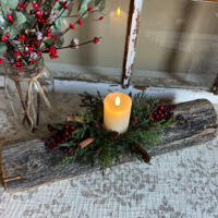A Christmas yule log candle centerpiece. It is made from upcycled wood with a white candle, greenery, and berries arranged on the top.   A Christmas yule log candle centerpiece. It is made from upcycled wood with a white candle, greenery, and berries arranged on the top.